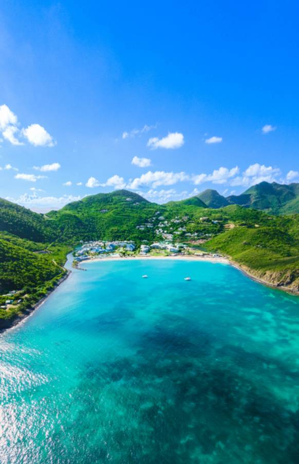 La baie Anse Marcel avec montagnes vertes et eau turquoise à Saint-Martin vue du ciel.