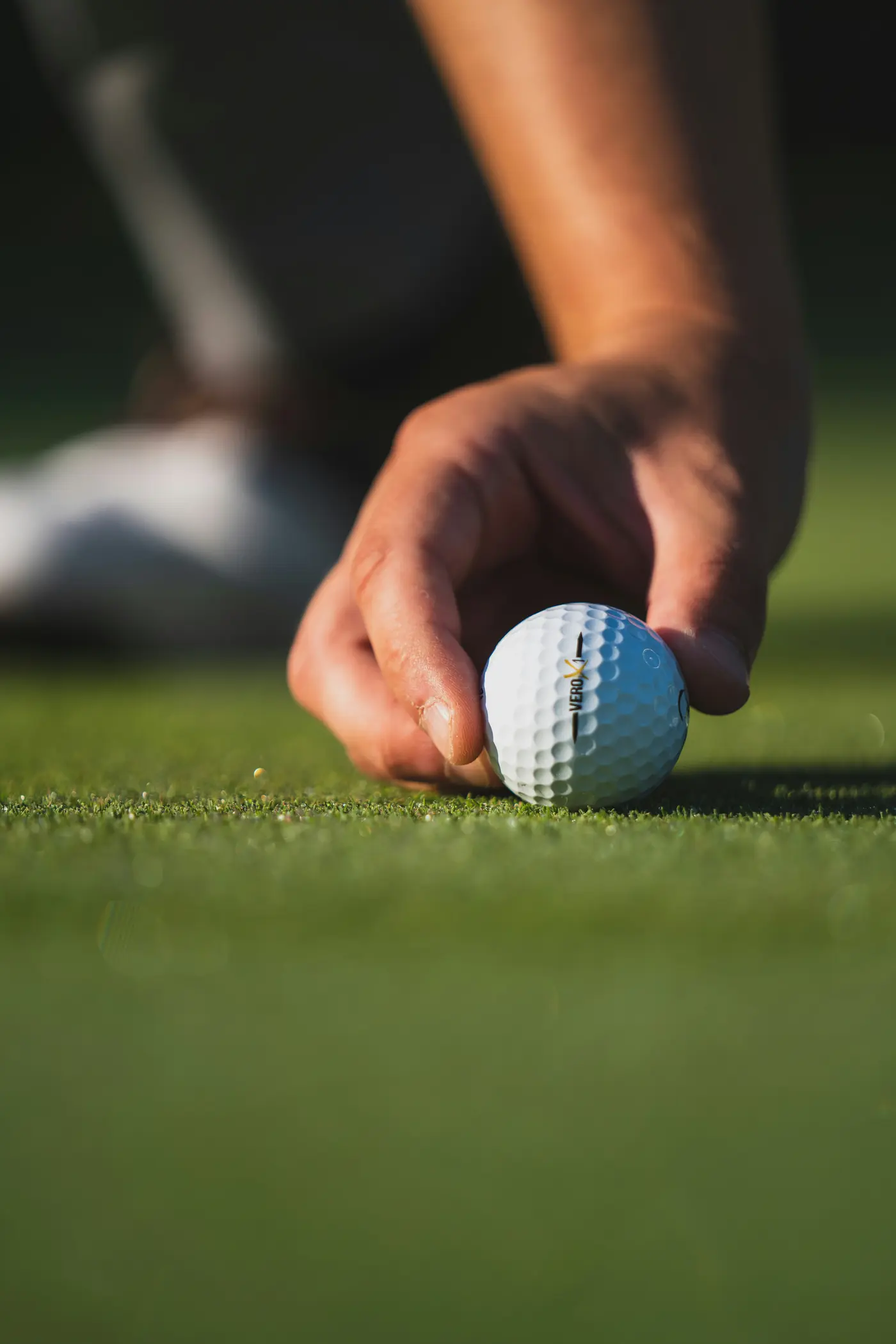 Hand placing a golf ball on a tee.