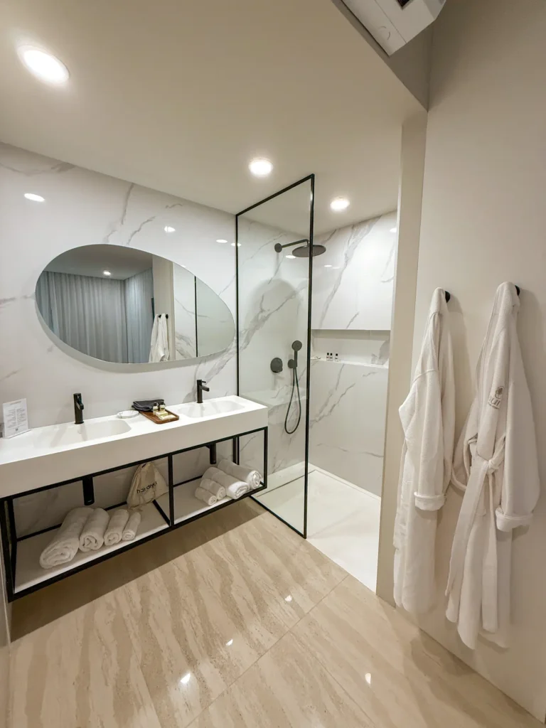 Marble bathroom with walk-in shower and bathrobes.