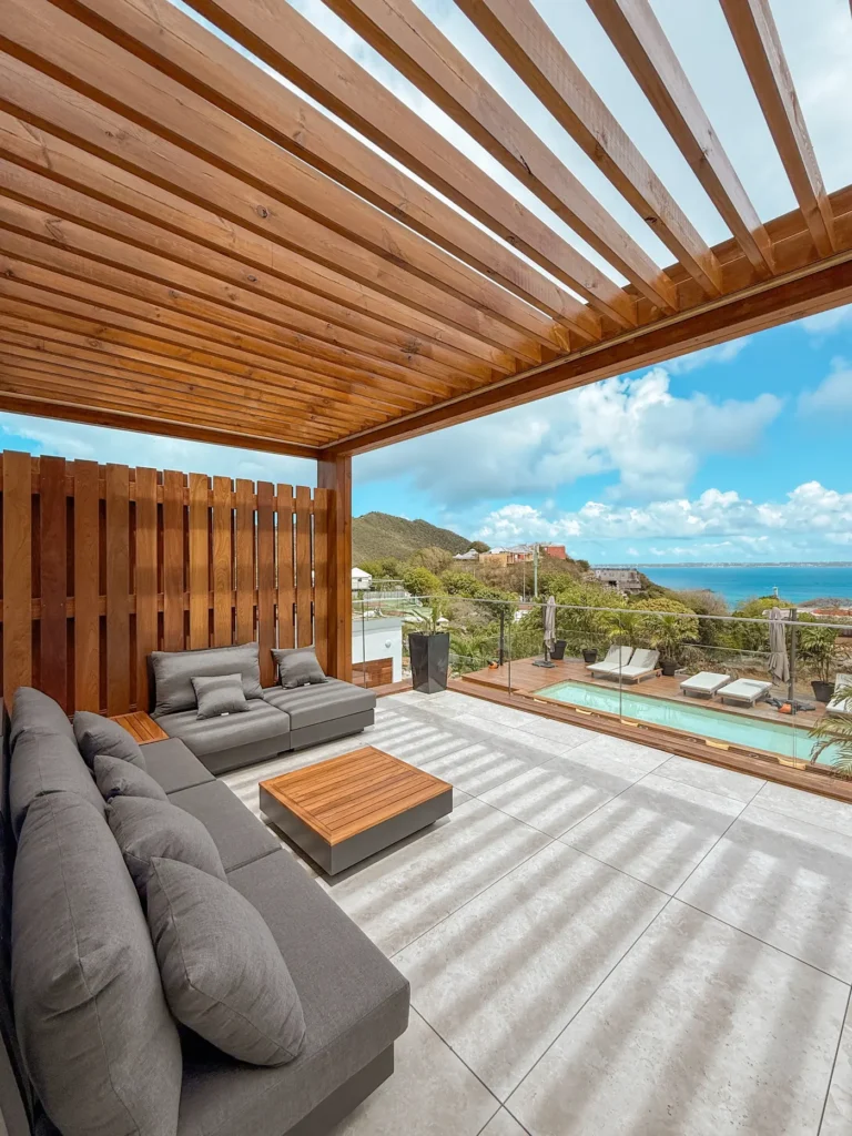 Outdoor sofa on a terrace under a wooden pergola.