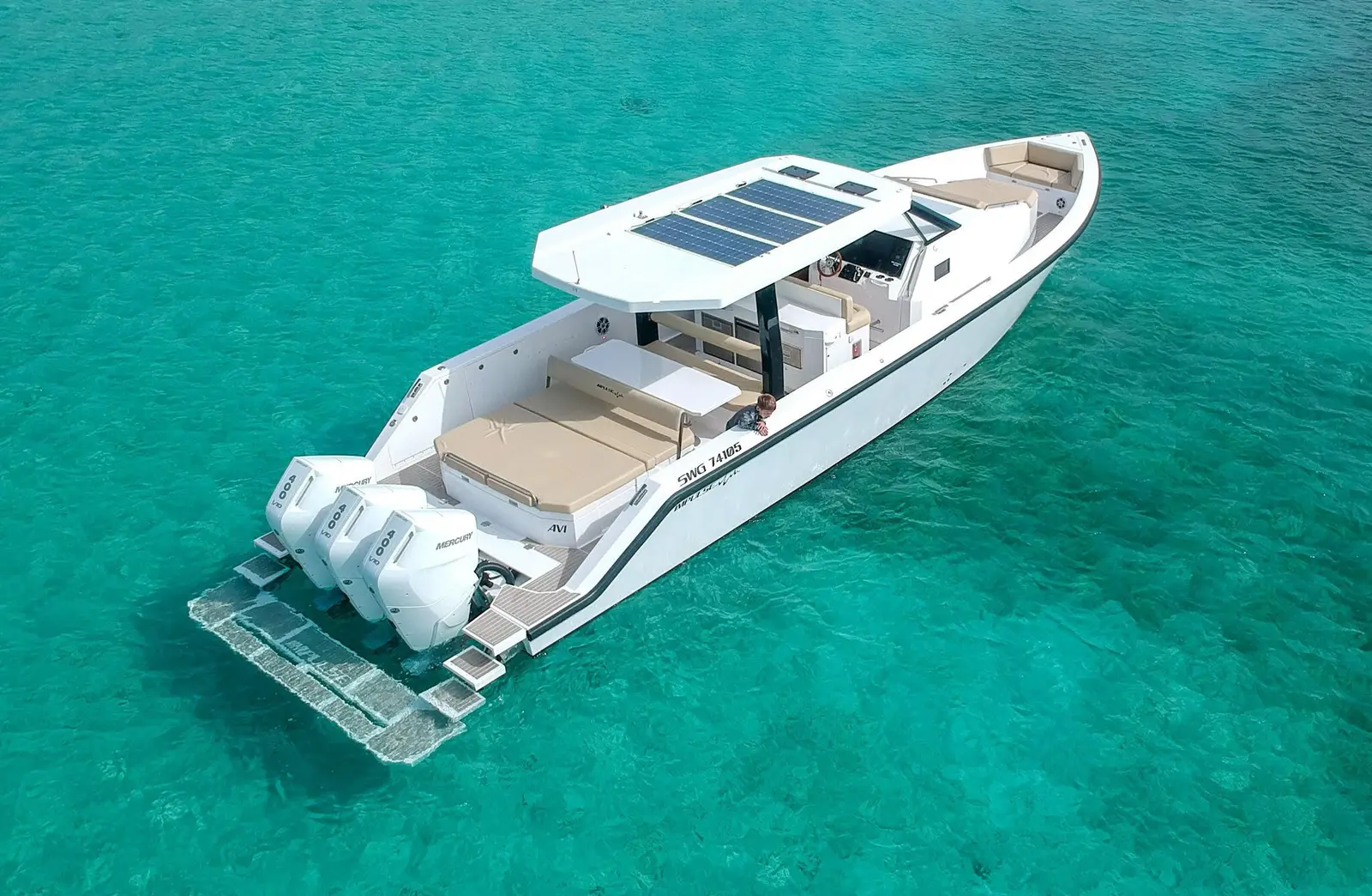 Large motor boat with sun pads on turquoise water.