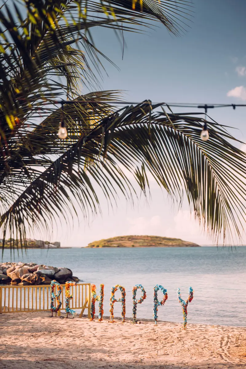 Flower letters spelling Be Happy on a beach.